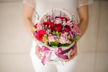 Close up of a woman holding small basket with flowers