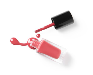 Spilled color nail polish with bottle and brush on white background, top view