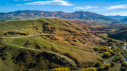 Naklejka premium Road running through hills and farmland. Otago, South Island, New Zealand