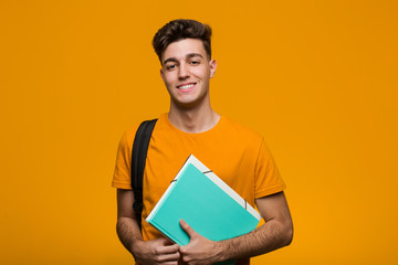 Fototapeta Young student man holding books smiling and raising thumb up obraz