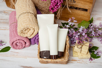Natural cosmetics with lilac flowers. Set of cream and towel rolls. Face care products. Prepare to bath. Spa therapy concept photo. Organic cosmetic on wooden background. relax and aromaterapy