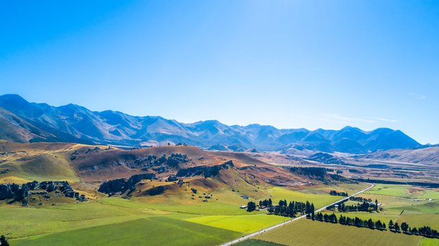 Road running through farmland with mountains on the background. West Coast, South Island, New Zealand © Dmitri