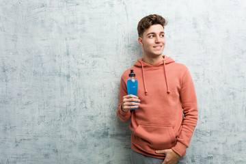 Young sport man holding an energy drink smiling confident with crossed arms.