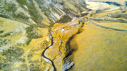 River running across farmland with mountains on the background. West Coast, South Island, New Zealand.