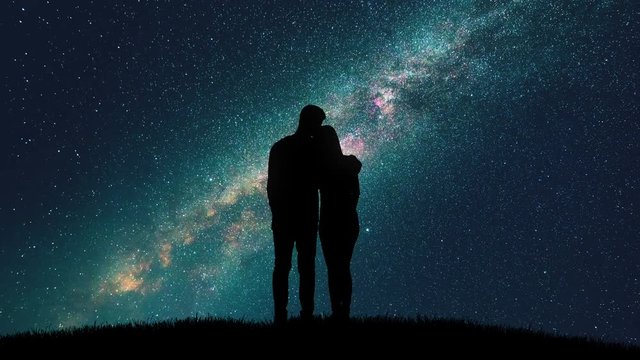 The man and woman hug on the starry sky background. time lapse