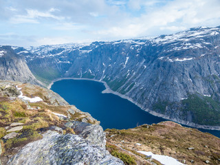 A beautiful view from the above on Ringedalsvatnet lake, Norway. Lake is located in between tall mountains. Slopes of the mountains are partially covered with snow. The water of the lake is navy blue.