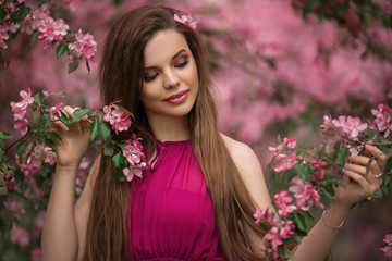 Closeup romantic portrait of young beautiful woman in blossom apple garden with pink flowers