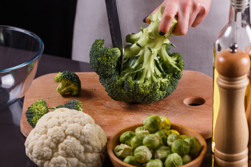 young woman in a gray aprons cuts cauliflower broccoli