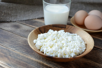 Cottage cheese in a wooden bowl, milk in a glass, eggs. Farm products. Village Breakfast