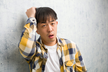 Young chinese man face closeup worried and overwhelmed