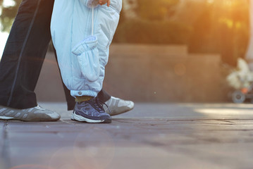 The baby learns to walk. Boy in blue overalls. Close-up legs.