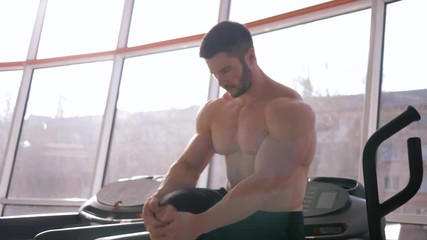 healthy lifestyle, attractive strong sportsman guy does warm-up after strength workout in building muscle in sports center against window