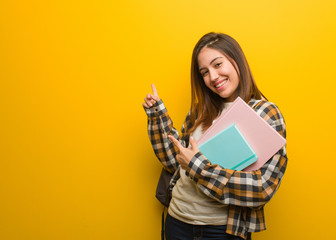 Young student woman pointing to the side with finger - obrazy, fototapety, plakaty