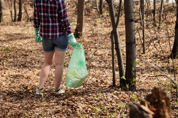 woman picking up dump on dirty forest