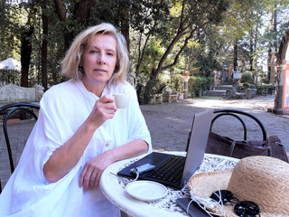 Cheerful mature woman using laptop computer while resting at the park