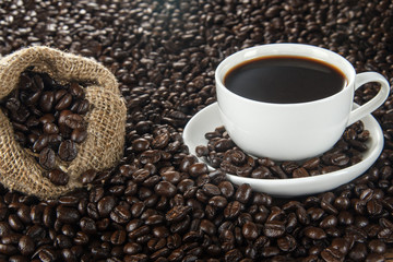 Cup of coffee and burlap bag on background of coffee beans.