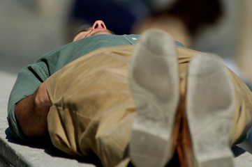  image of a man sleeping on a bench in the street