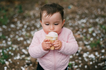 little girl in the garden on the background of greenery and trees very cute eating ice cream in a waffle Cup