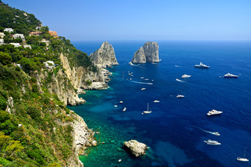 Capri coast view with the Faraglioni rocks and boats in the blue sea, Italy