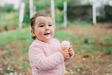 little girl in the garden on the background of greenery and trees very cute eating ice cream in a waffle Cup
