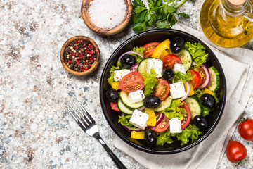 Greek salad in black plate on the table.