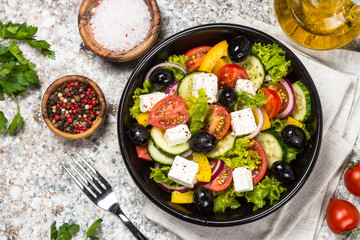 Greek salad in black plate on the table.