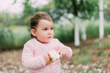 little girl in the garden on the background of greenery and trees very cute eating ice cream finger in a waffle Cup