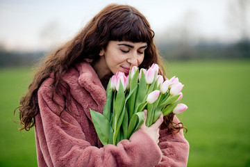 Young woman with bouquet of tulips and pink coat