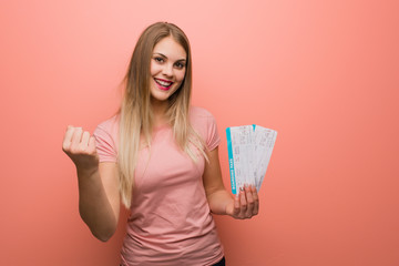 Young pretty russian girl surprised and shocked. She is holding an air tickets.