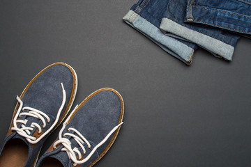 Classic blue jeans and denim shoes. Flat lay set of stylish clothes and accessories on dark background, top view, fashion concept, copy space for text