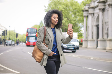 Business woman walking in the street, checking her smart phone
