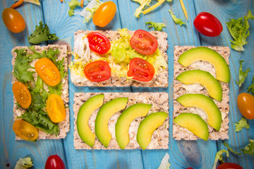 Healthy snack from wholegrain rye crispbread cracker with cherry tomatoes, avocado and salad. Proper nutrition.