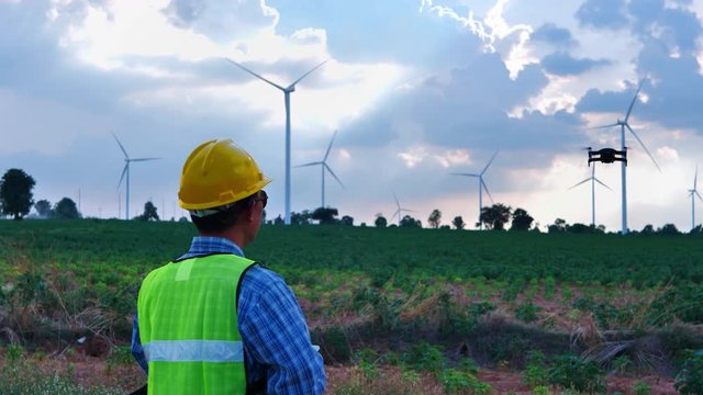 Engineers male are checking the operation of wind turbines in wind farm field with Inspection drone for production of electric power.