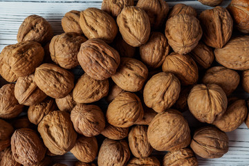 WALNUT NUTS IN A SHELL SPREADED ON A WHITE WOODEN BACKGROUND FLAT LAY
