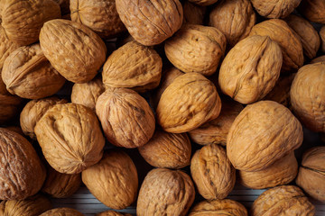 WALNUT NUTS IN A SHELL SPREADED ON A WHITE WOODEN BACKGROUND FLAT LAY