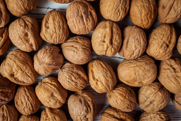 WALNUT NUTS IN A SHELL SPREADED ON A WHITE WOODEN BACKGROUND FLAT LAY