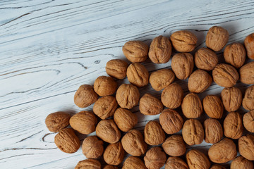 WALNUT NUTS IN A SHELL SPREADED ON A WHITE WOODEN BACKGROUND FLAT LAY