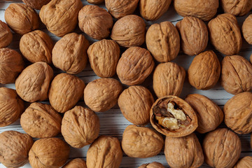 WALNUT NUTS IN A SHELL SPREADED ON A WHITE WOODEN BACKGROUND FLAT LAY