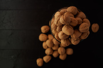 WALNUT NUTS IN A SHELL SPREADED ON A COAL BLACK WOODEN BACKGROUND FLAT LAY