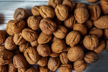 WALNUT NUTS IN A SHELL SPREADED ON A WHITE WOODEN BACKGROUND FLAT LAY