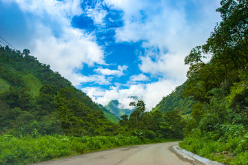 Fototapeta na wymiar South America. Ecuador. Andes mountains covered with greenery. An asphalt road leads to Andes mountains. Landscape of Ecuador. Sightseeing In Ecuador.