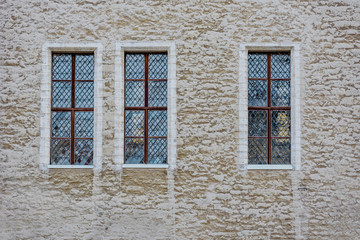Three windows on light brown brick wall background