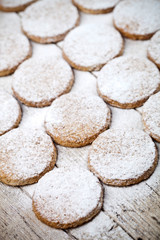 Fresh baked oat cookies with sugar powder on rustic wooden table background.