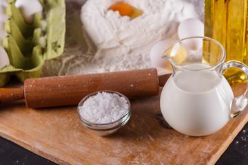 young woman in apron kneading dough on board