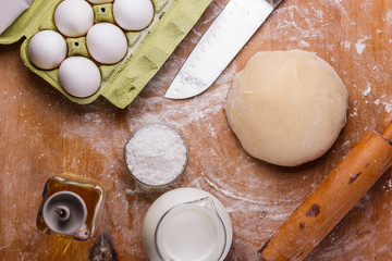 young woman in apron kneading dough on board