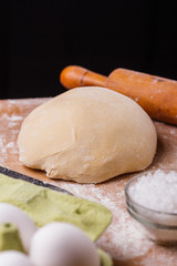 young woman in apron kneading dough on board