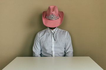 cowboy with pink hat behind a white table