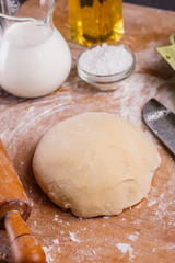 young woman in apron kneading dough on board