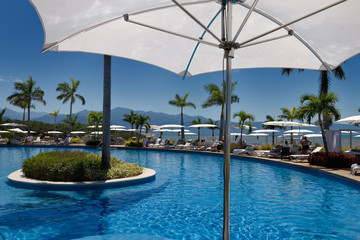 Under an umbrella poolside on the Pacific ocean with Sierra Madre mountains Mexico