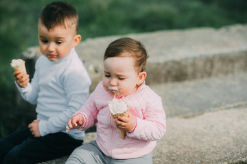 Little kids brother and sister eating ice cream outdoors